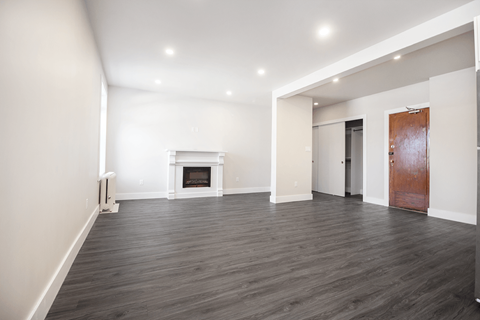 a living room with white walls and a fireplace and a wooden door