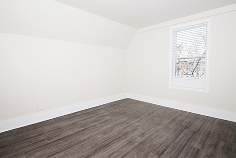 an empty room with white walls and wood floors and a window