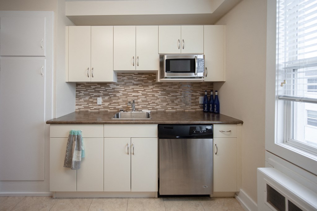 a kitchen with white cabinets and a counter top with a sink and a microwave