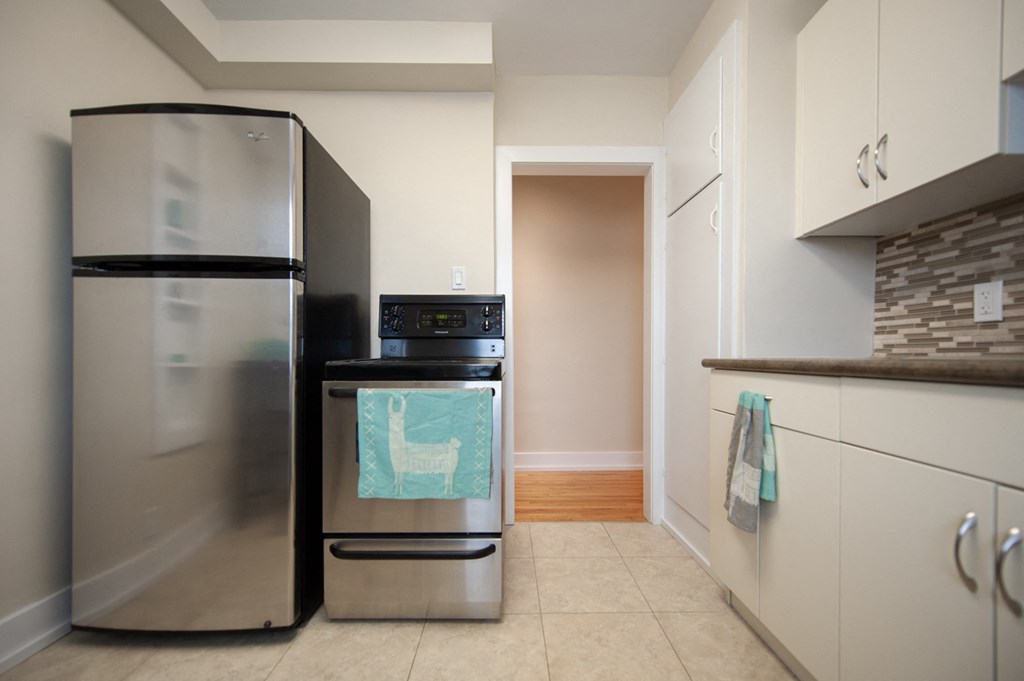 a kitchen with a stainless steel refrigerator and stove and white cabinets