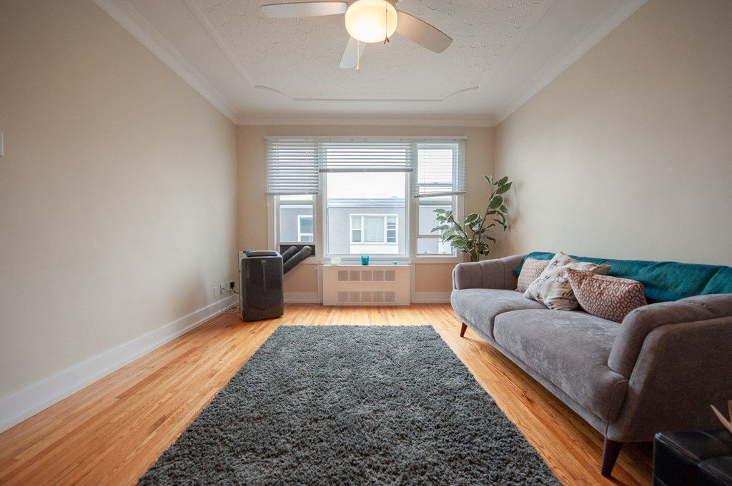 a living room with a couch and a ceiling fan and a window