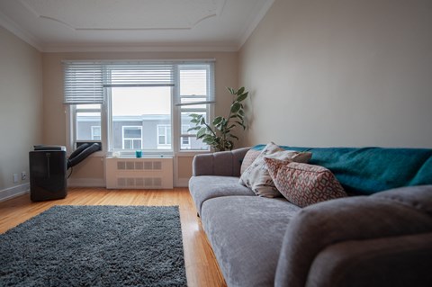 A living room with a grey couch and a black speaker.
