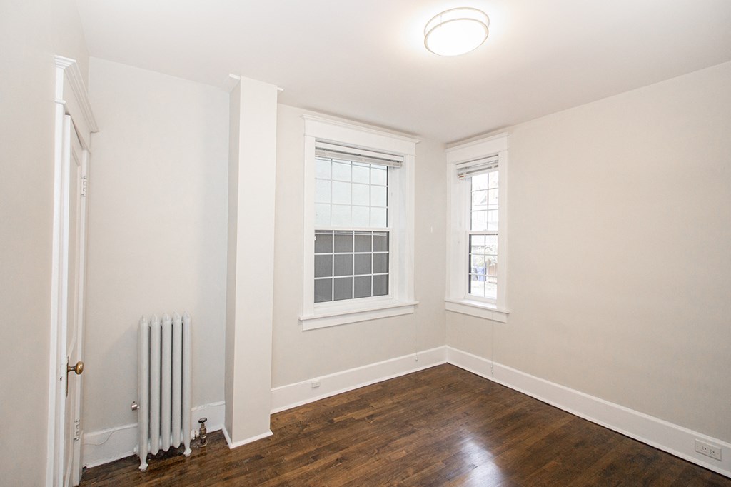 a living room with white walls and wood floors at 883 Grosvenor Avenue Apartments