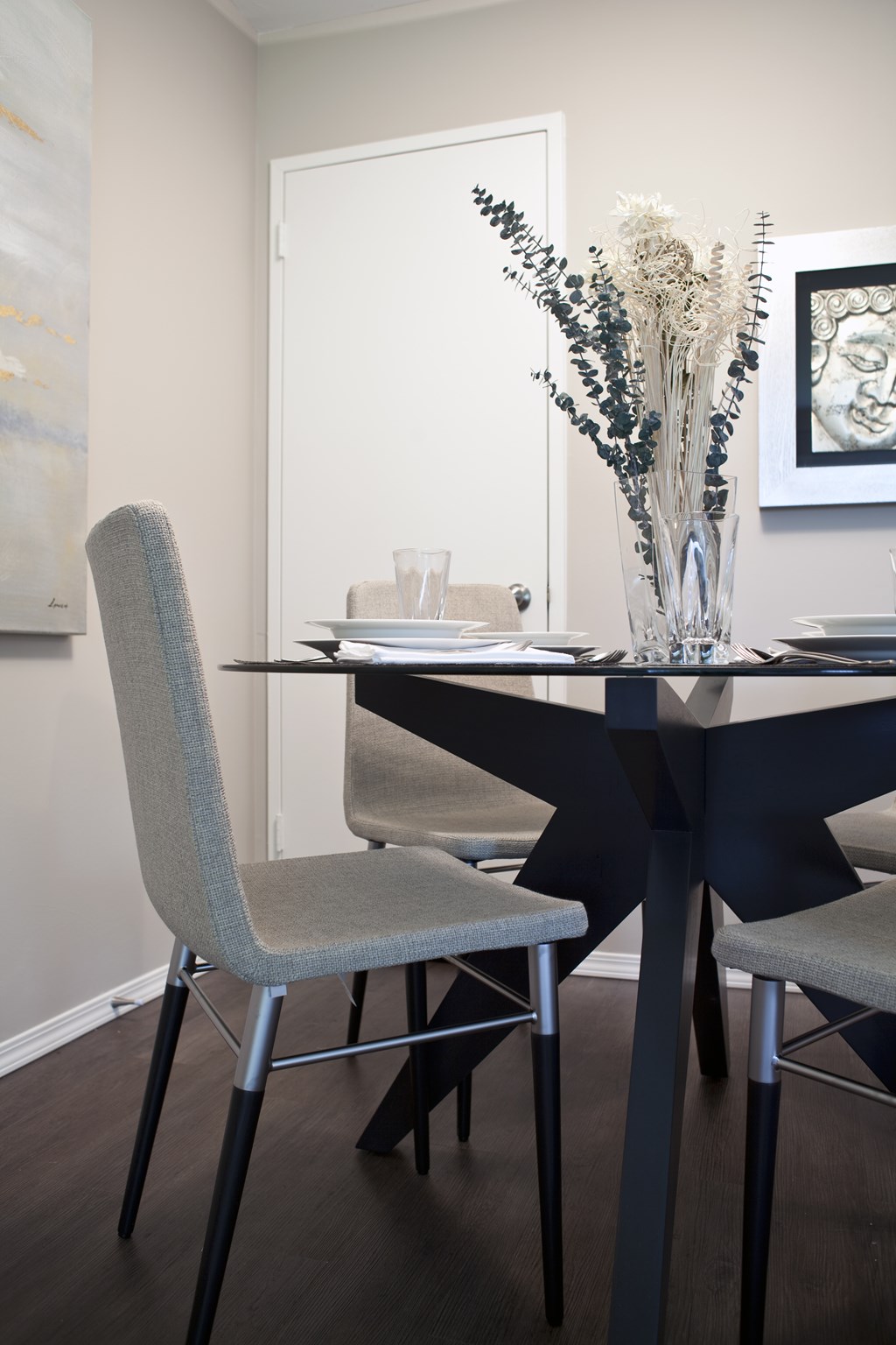 A dining table with chairs and a vase of flowers.