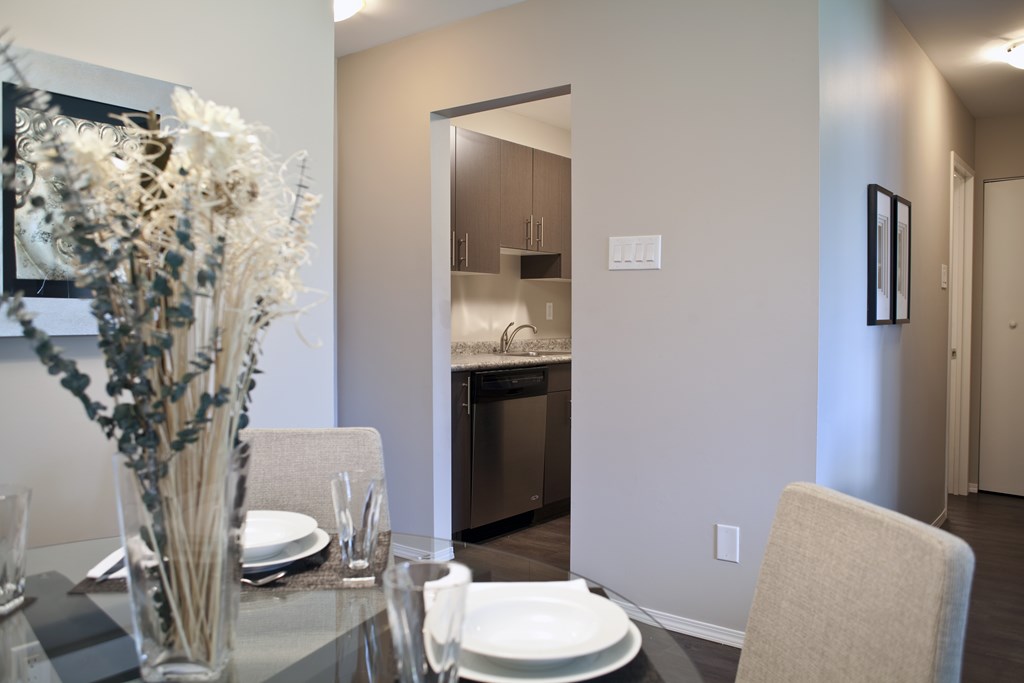A dining table with a vase of flowers and plates on it.
