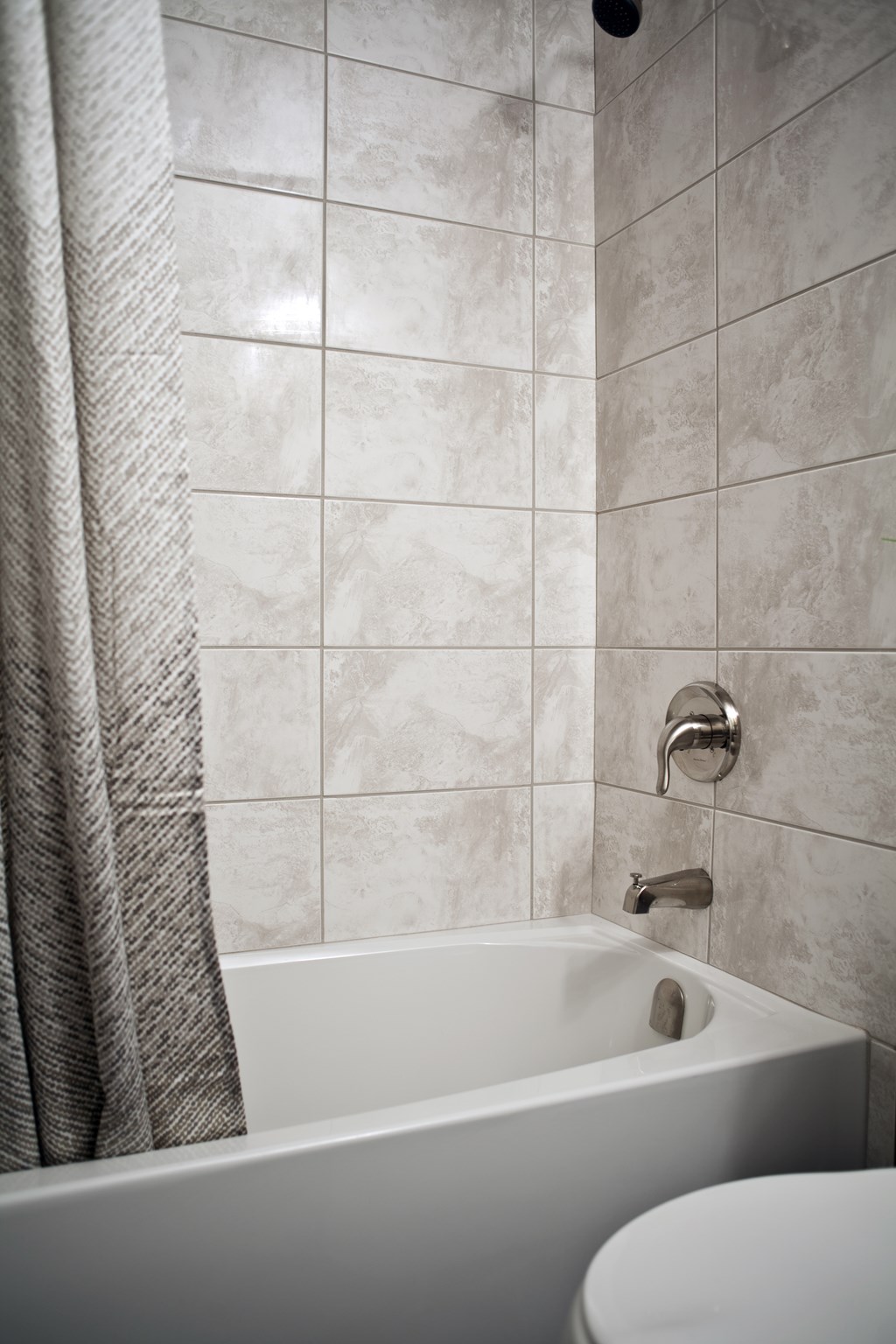 A white bathtub with a shower curtain and a shower head.