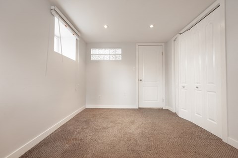 a bedroom with white walls and carpet and two white doors