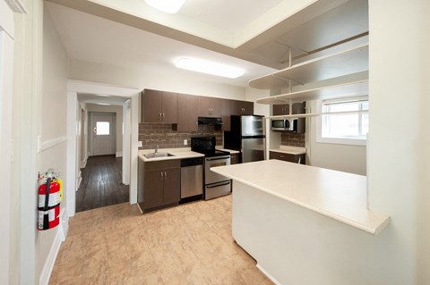 A kitchen with a white counter and brown cabinets.