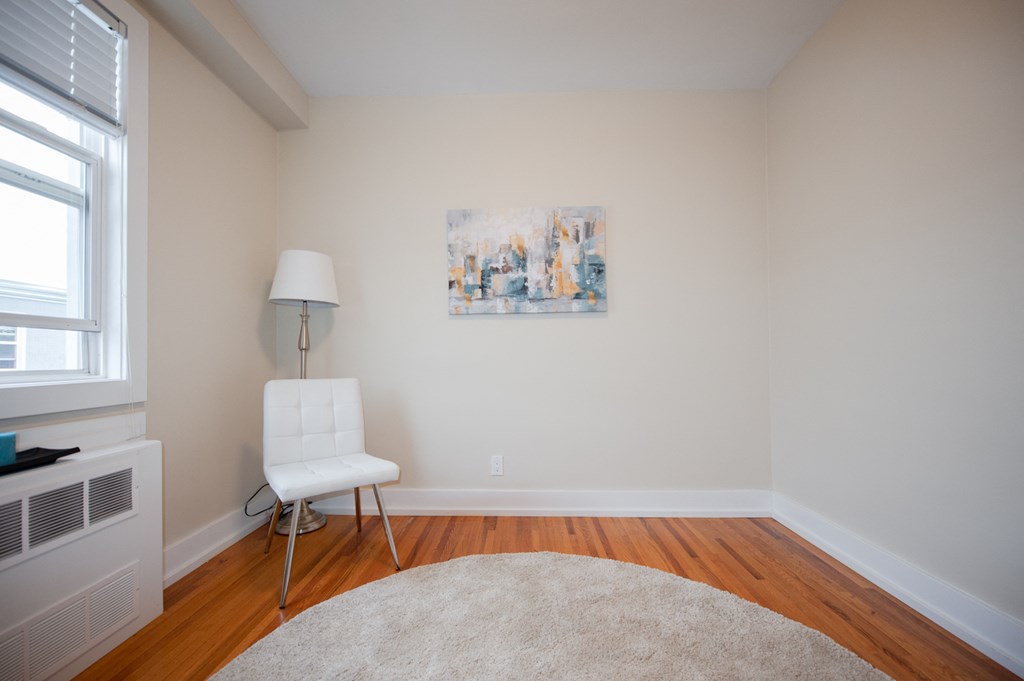 a living room with a chair and a white rug and a painting on the wall