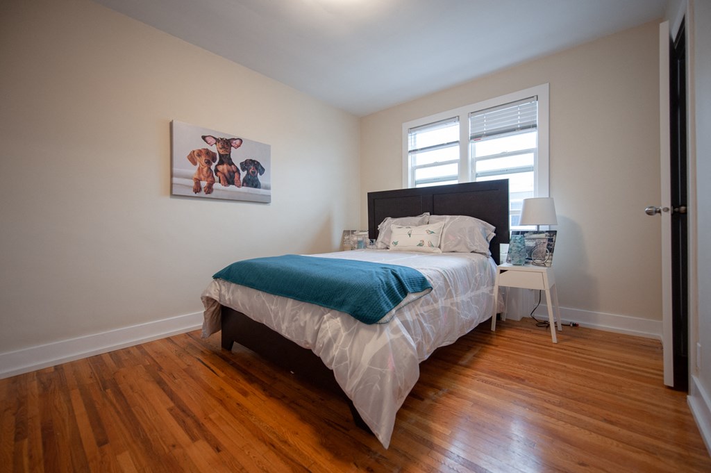 a bedroom with a bed and a window and wood floors