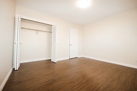 a bedroom with wood flooring and white walls and a closet