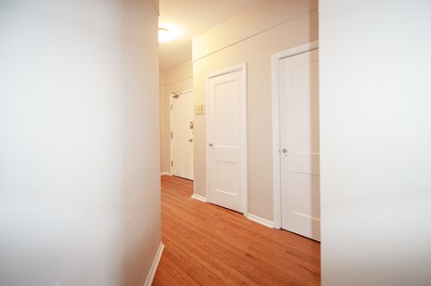 a bedroom with wood flooring and white walls and doors