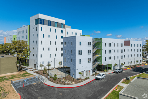 A modern multi-story building with a white exterior and a red curved walkway in front.