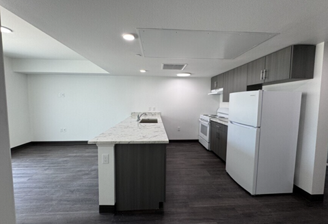 A kitchen with a white fridge and a marble island.
