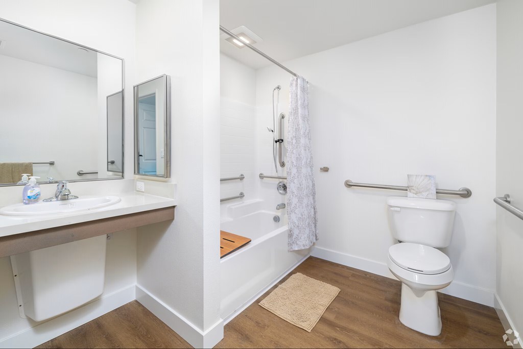 A white toilet is in a bathroom with a white sink and a white shower curtain.