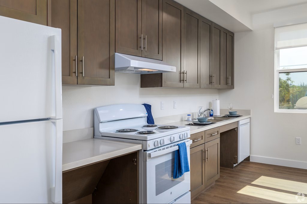A kitchen with a white fridge, stove, and cabinets.