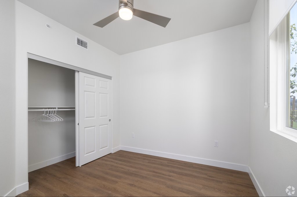 A room with a ceiling fan and a doorway leading to another room.