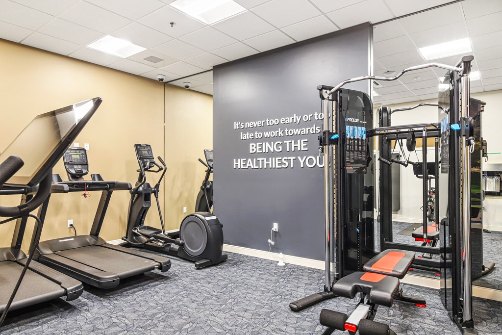a gym with exercise equipment and a wall with a quote on it