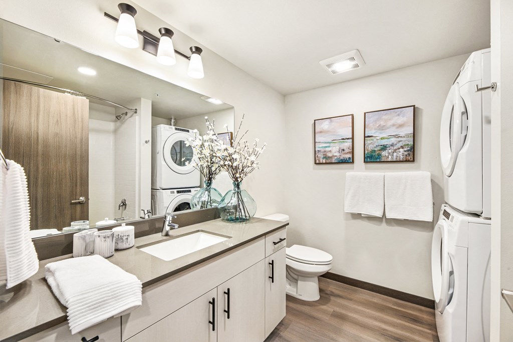 a white bathroom with a large mirror and a washer and dryer