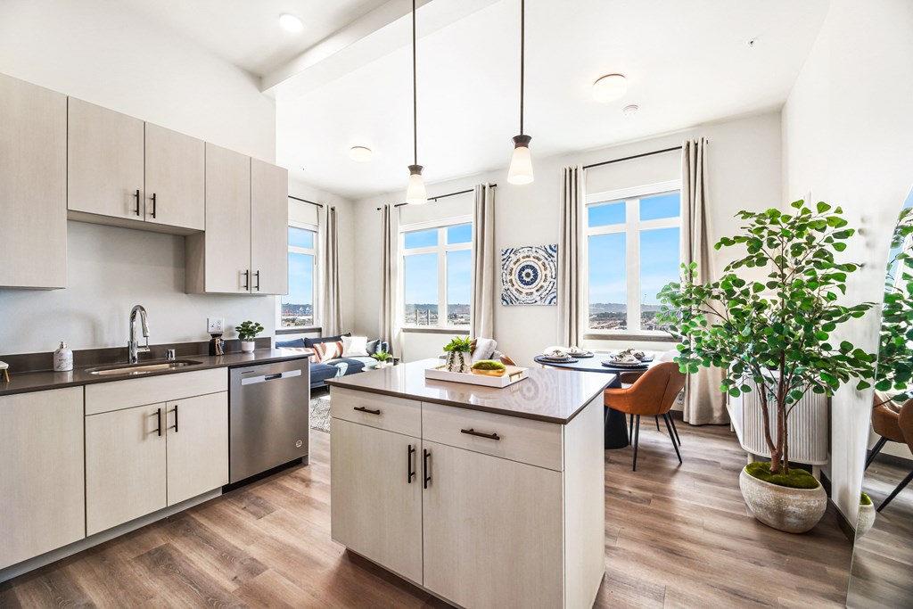 a kitchen and living room with a large window and a table with a plant