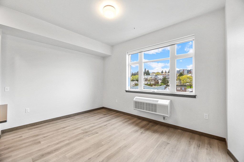 an empty living room with a large window and wood flooring