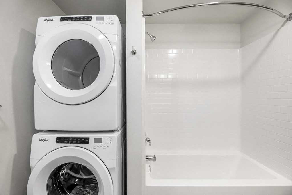 a washer and dryer in a bathroom next to a shower and a tub