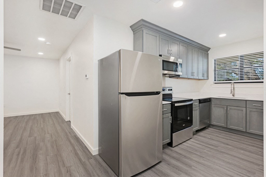 a kitchen with gray cabinets and a stainless steel refrigerator
