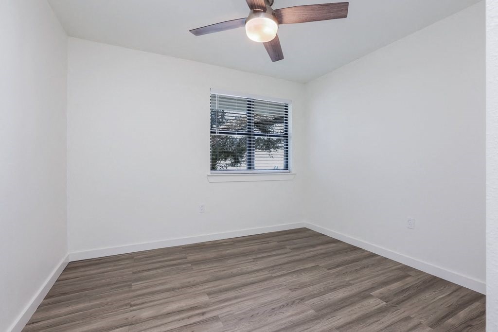 a bedroom with white walls and a ceiling fan