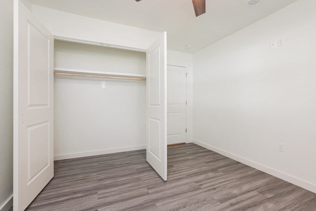 a bedroom with white walls and a wooden floor
