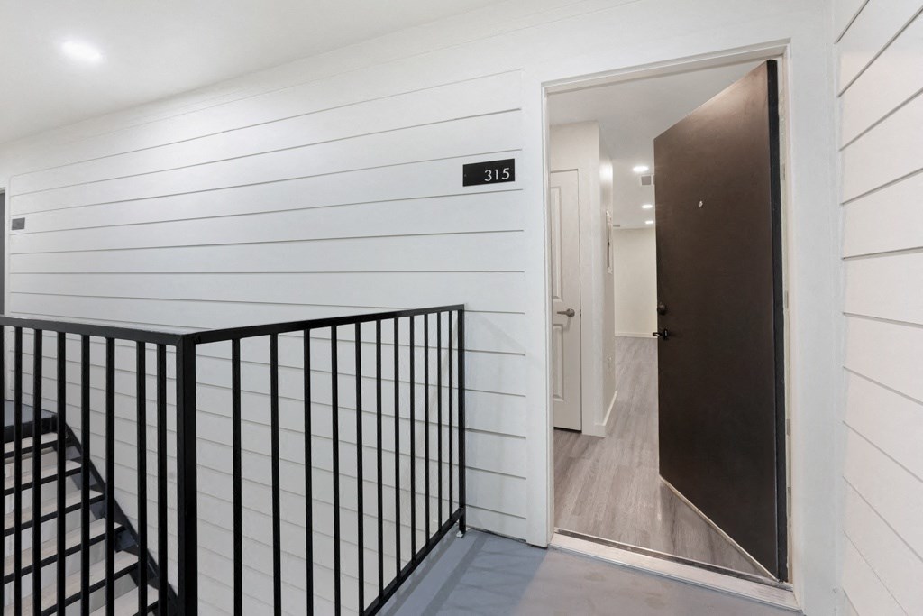 a foyer with white shiplap walls and a dark brown door
