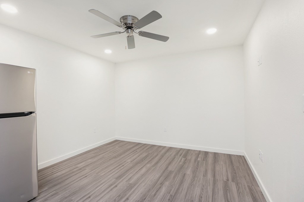 a bedroom with white walls and a ceiling fan