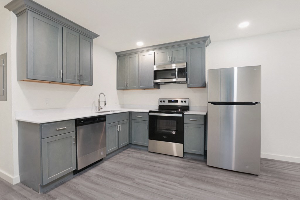 a kitchen with gray cabinets and stainless steel appliances
