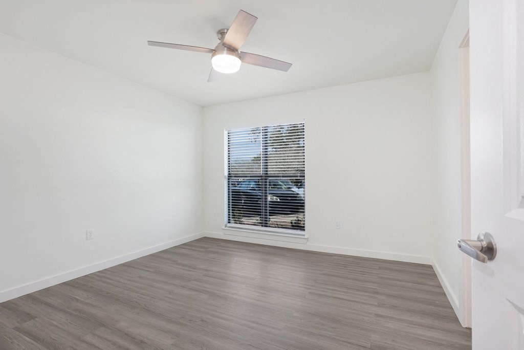 a bedroom with hardwood floors and a ceiling fan