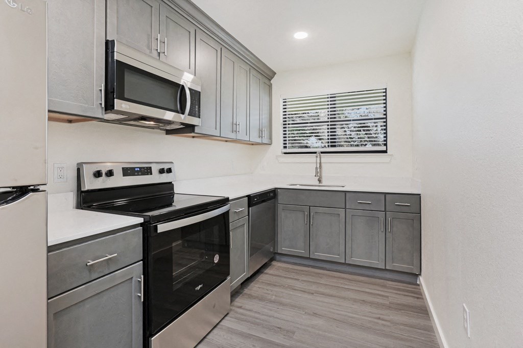 a kitchen with gray cabinets and white countertops