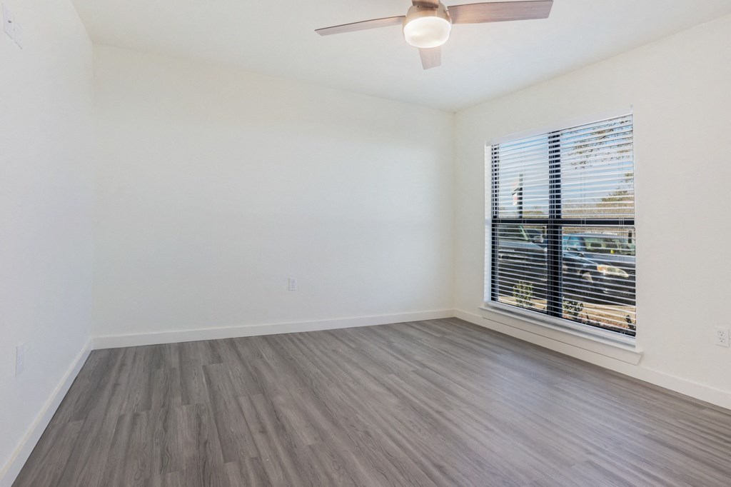 an empty bedroom with a large window and a ceiling fan
