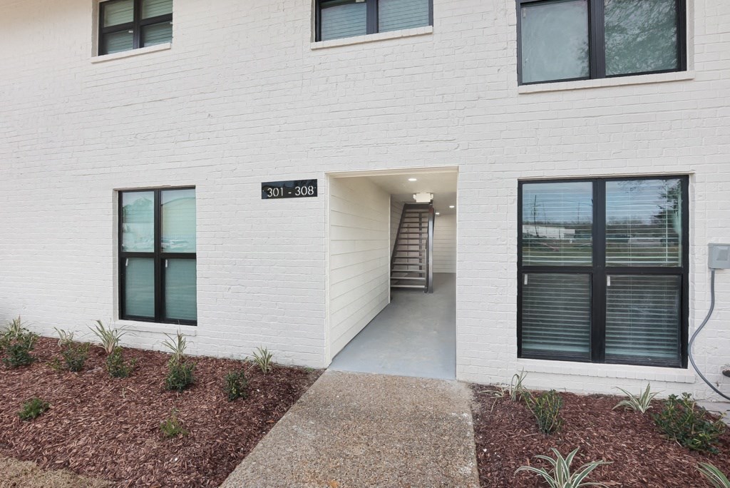 a walkway leads to a door in a white brick building