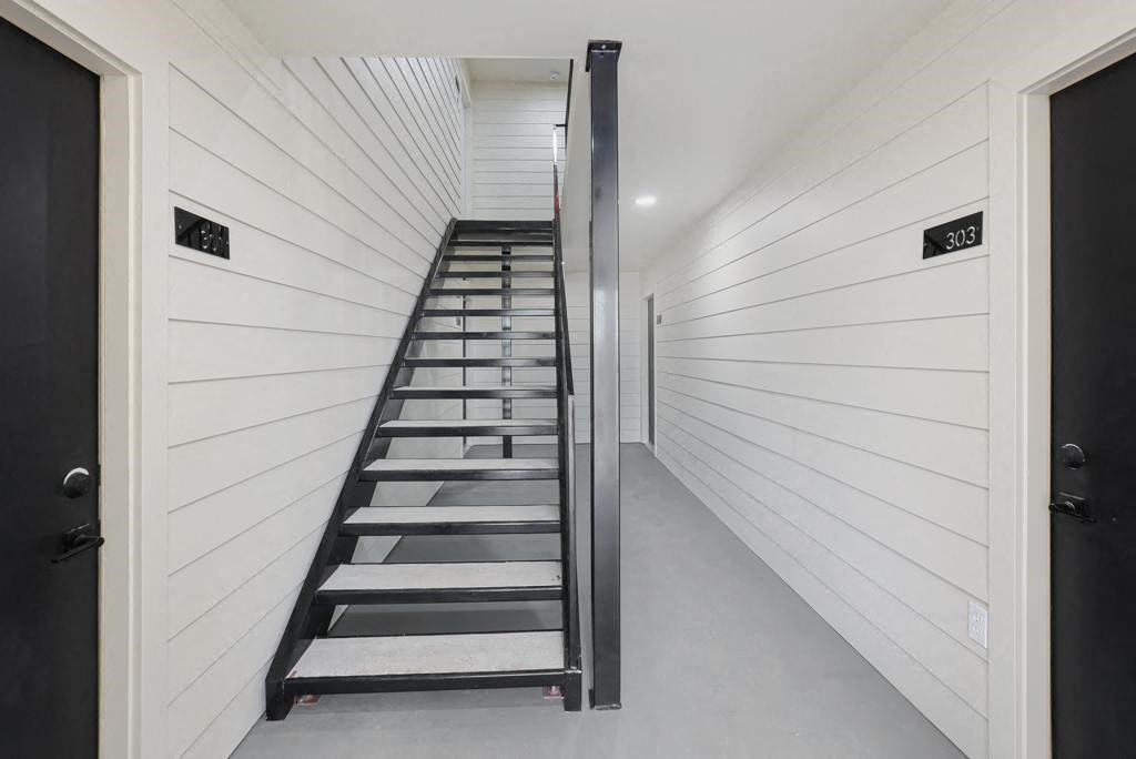 a staircase in a house with white walls and a black door