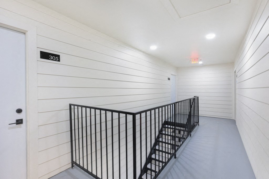 a long staircase with wrought iron railings and a white door