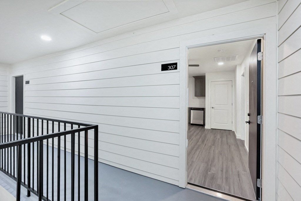 a hallway in a home with white walls and a gray floor