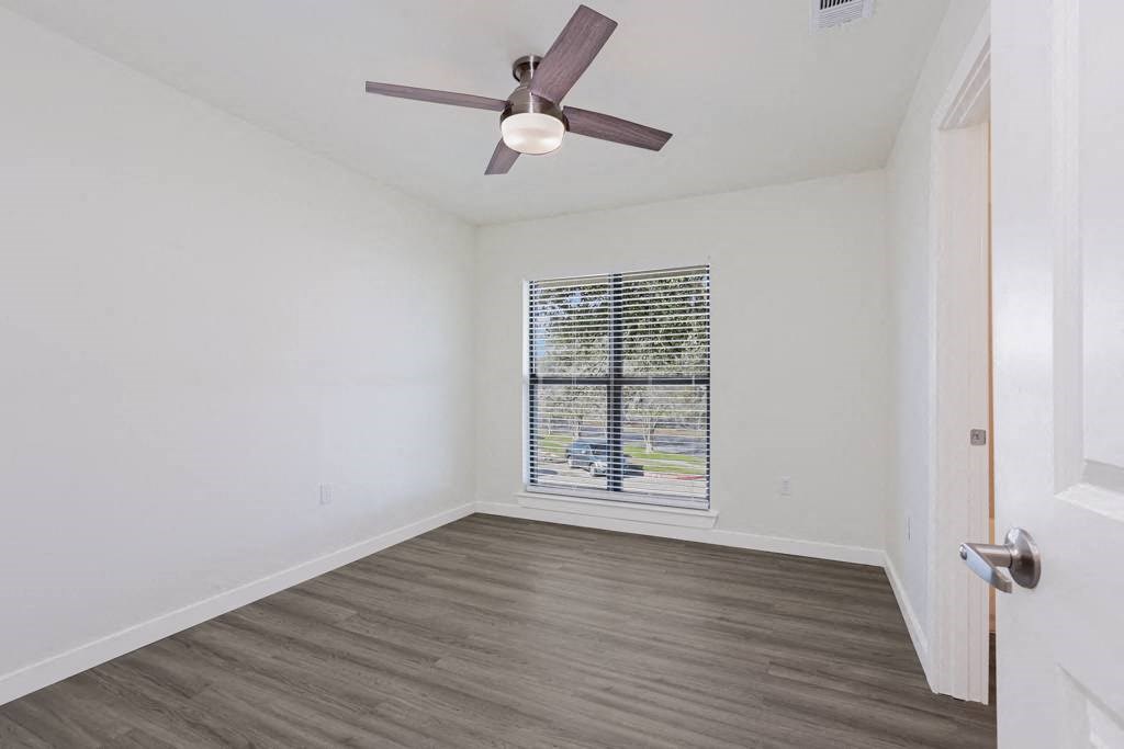a bedroom with a large window and a ceiling fan