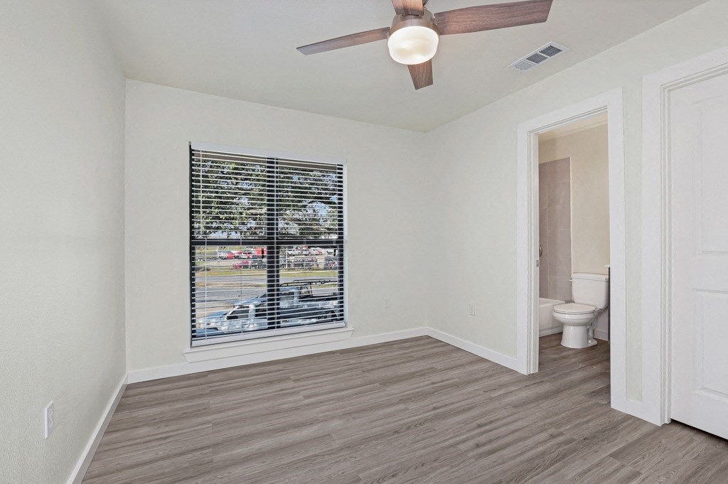 a bedroom with a large window and a ceiling fan