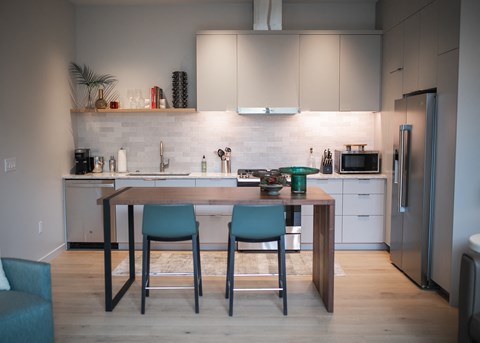 A kitchen with a table and chairs in front of it.