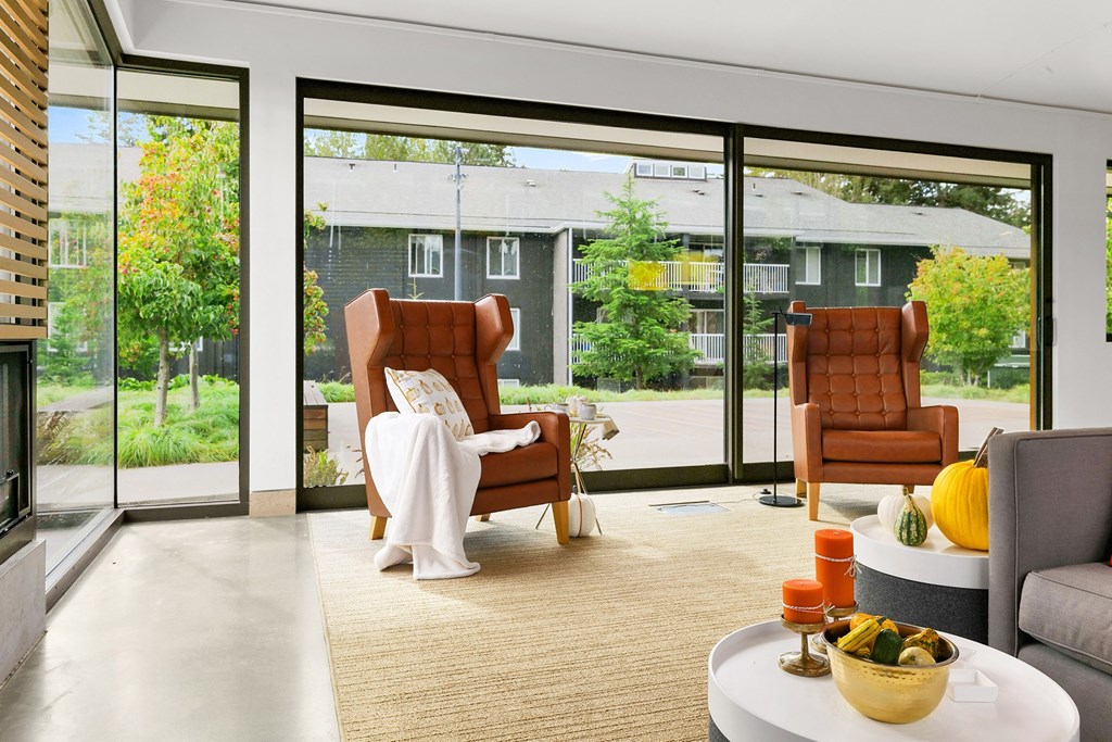a living room with chairs and a table and large windows