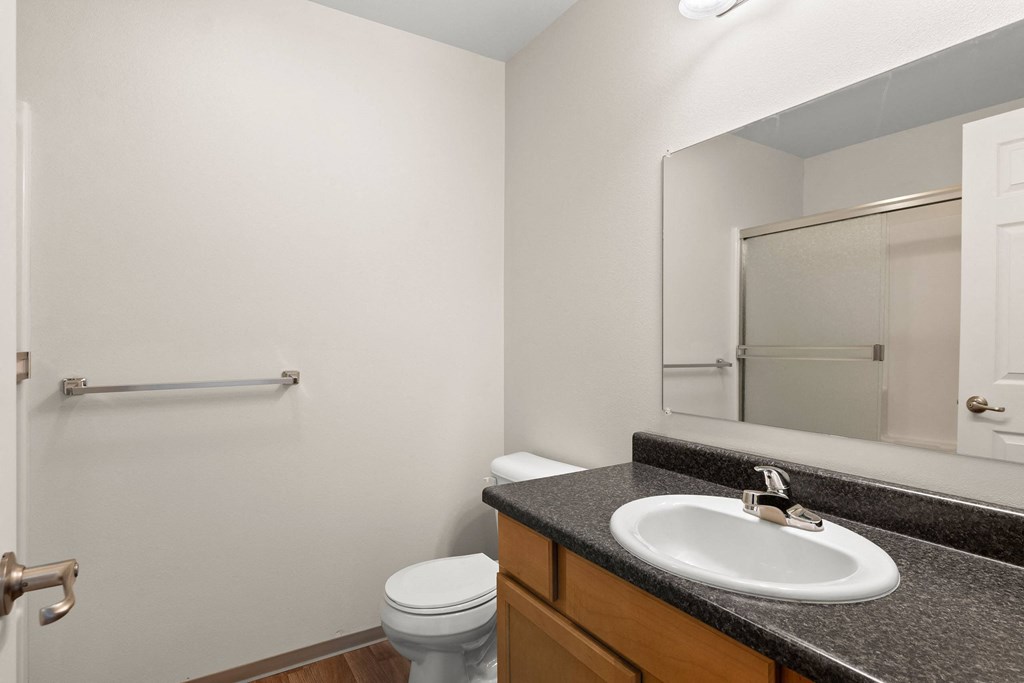 a bathroom with a sink and mirror and a toilet at Trillium Apartments, Springfield, OR, 97477