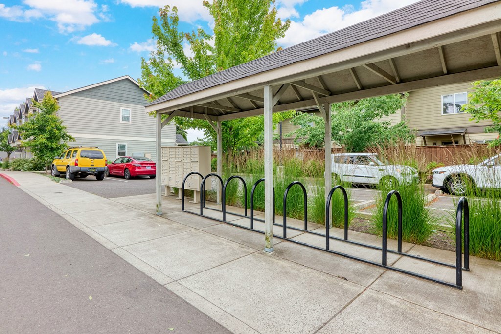 a covered parking lot with cars parked in front of a house at Trillium Apartments, Springfield, OR