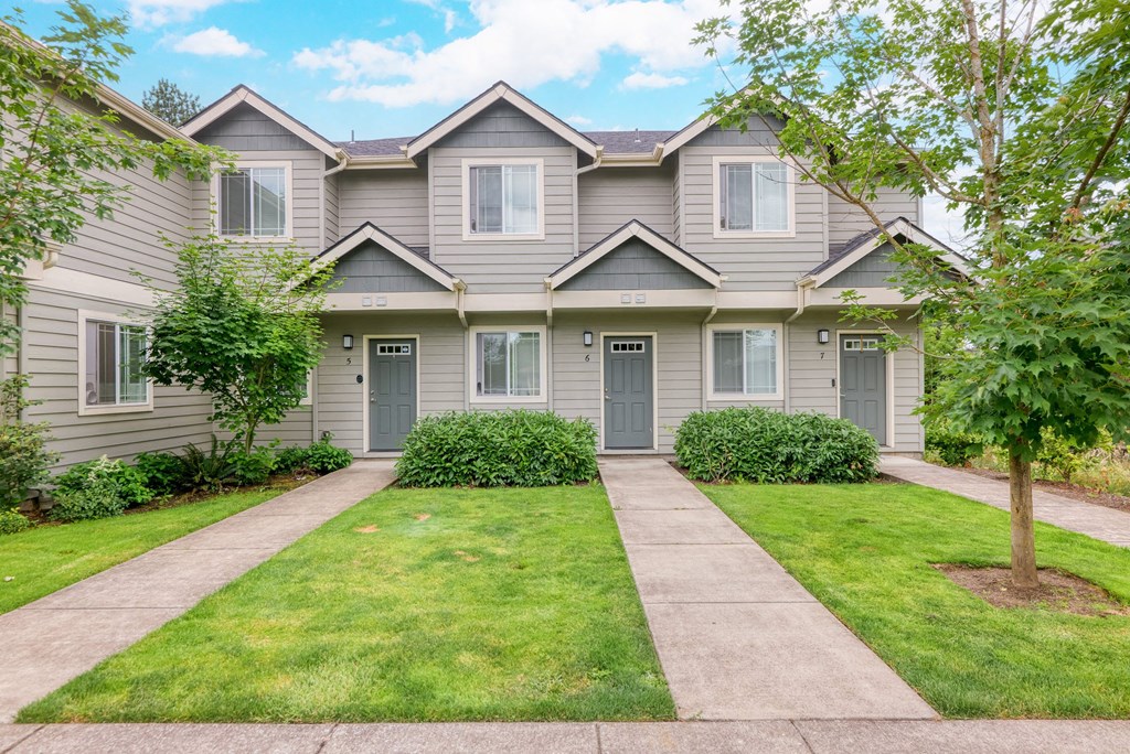 the front of a grey house with a sidewalk and grass at Trillium Apartments, Springfield, 97477