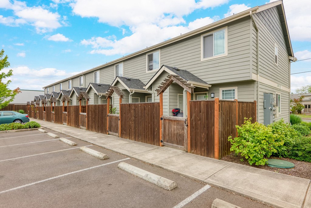 a row of houses with a wooden fence in front of a parking lot at Trillium Apartments, Oregon 97477