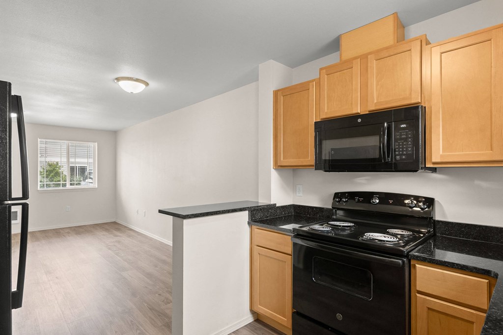 an empty kitchen with black appliances and wooden cabinets at Trillium Apartments, Springfield, 97477