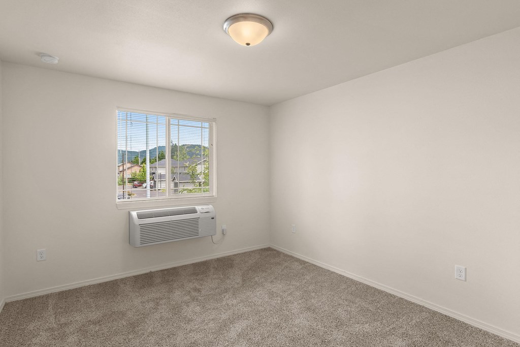 an empty room with a window and an air conditioner at Trillium Apartments, Springfield, 97477