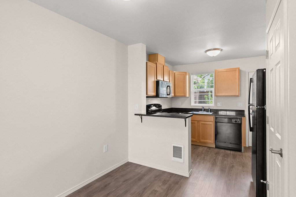 a view of a kitchen and a hallway with white walls and wood floors at Trillium Apartments, Springfield, 97477